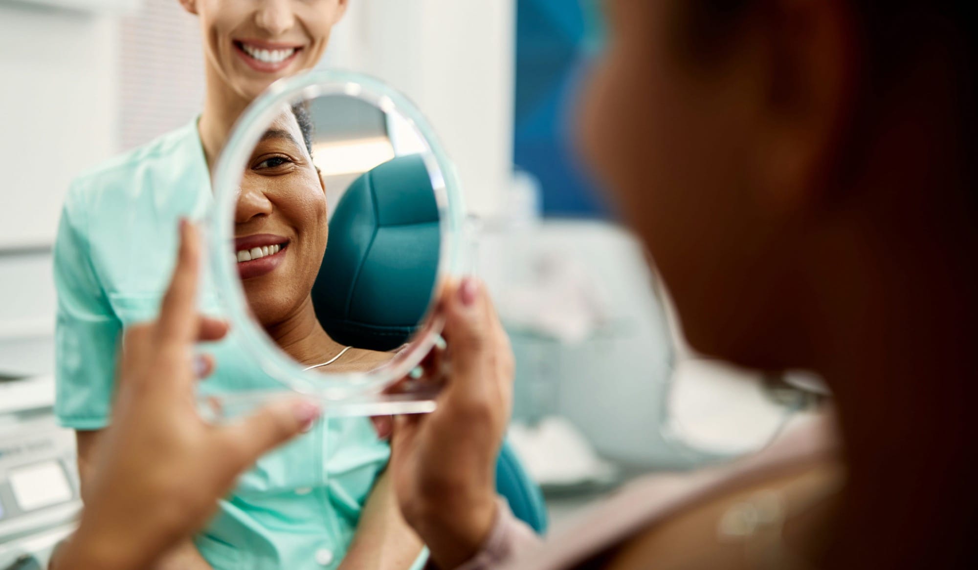 Patientin betrachtet ihr Lächeln im Spiegel: Nach Behandlung prüft eine Frau zufrieden das Ergebnis im Zahnarztzimmer.