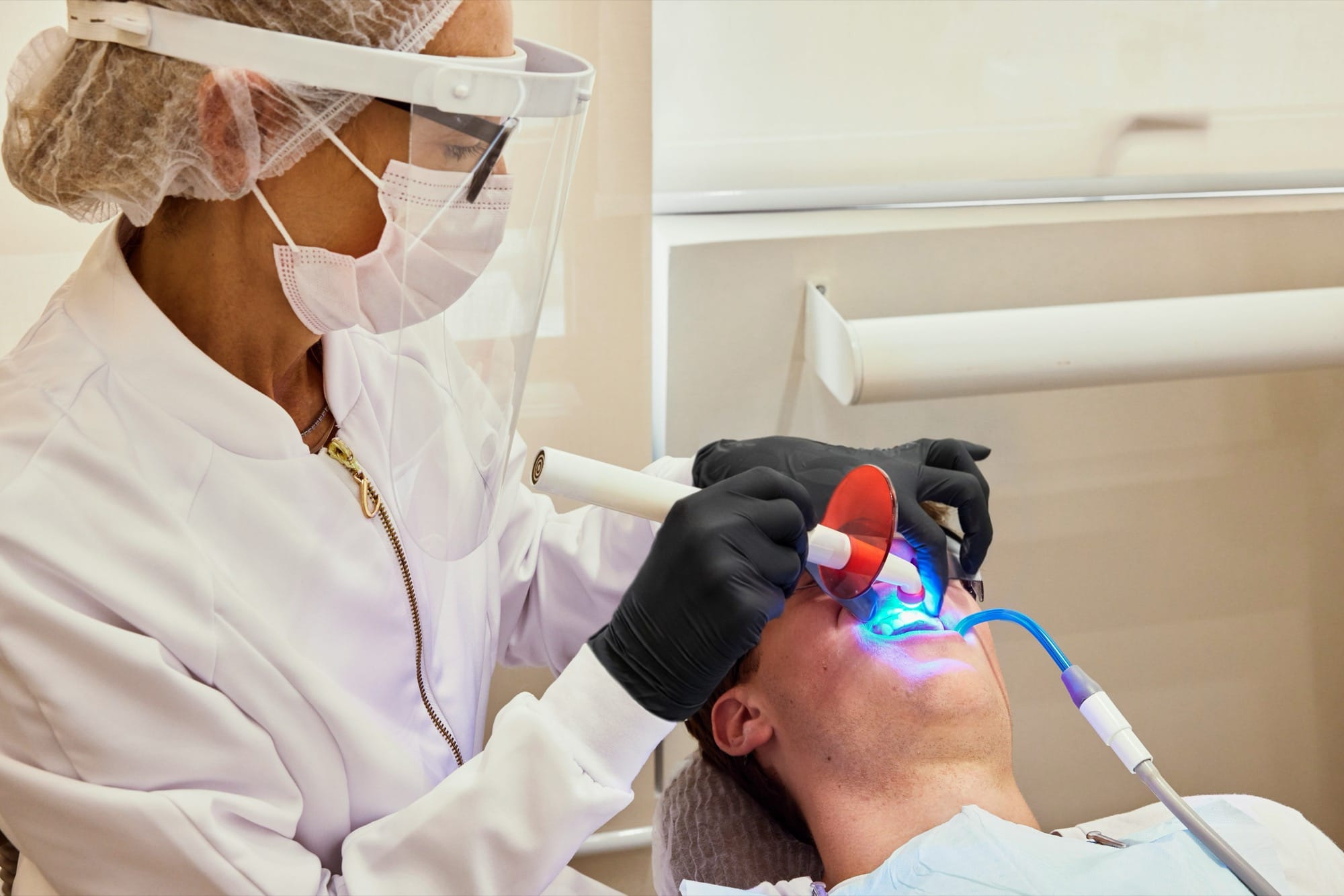 Zahnaufhellung mit Lichtgerät: Ein Patient erhält eine Behandlung mit blauem Licht zur Aufhellung der Zähne.